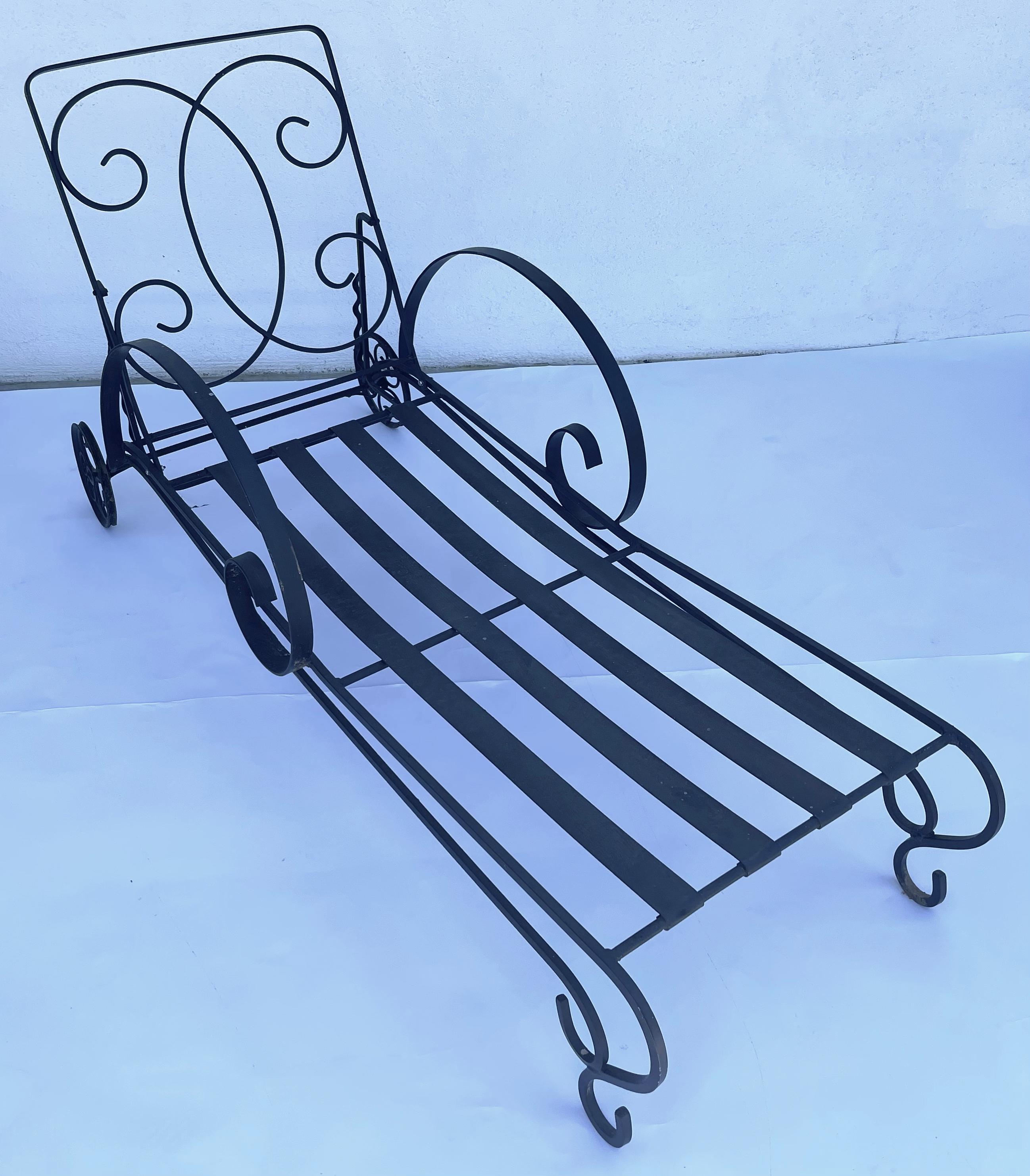 Pair of mid century black wrought iron Salterini Florentine chaise lounge chairs. Original matte black painted finish. Adjustable backrests are in good working order. Scrolled back detailing and curved arms. The chaises are heavy and well made.