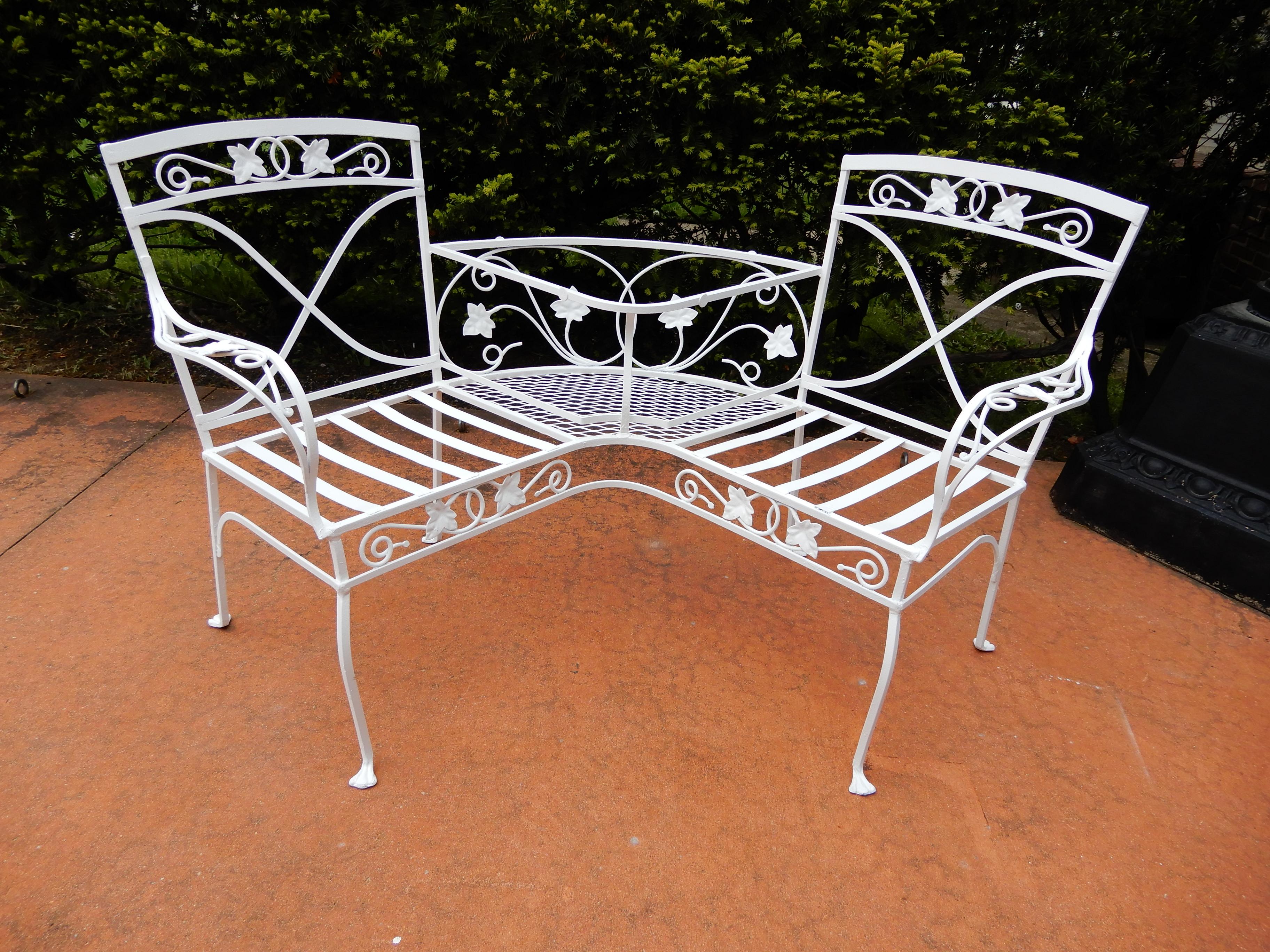 A Salterini wrought iron garden tete a tete, in the desirable Mt Vernon pattern. The piece is raised on 4 legs terminating in the paw foot. The two chairs are joined in the Center and a new glass should be placed in between the seats. The bench has