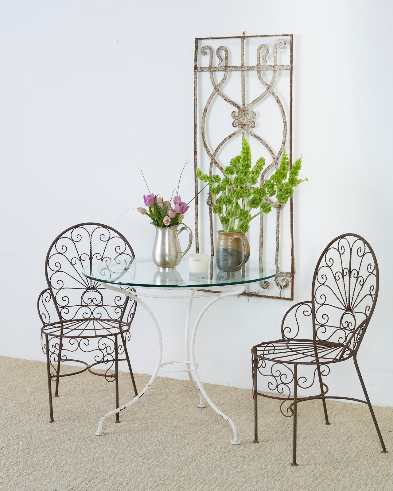 Set of four stunning iron garden or patio chairs featuring a fan back or peacock style. Made in the manner of Salterini. These chairs are handcrafted from wrought iron. Decorative scrolls made of twisted wire fill the backs and seat apron. The