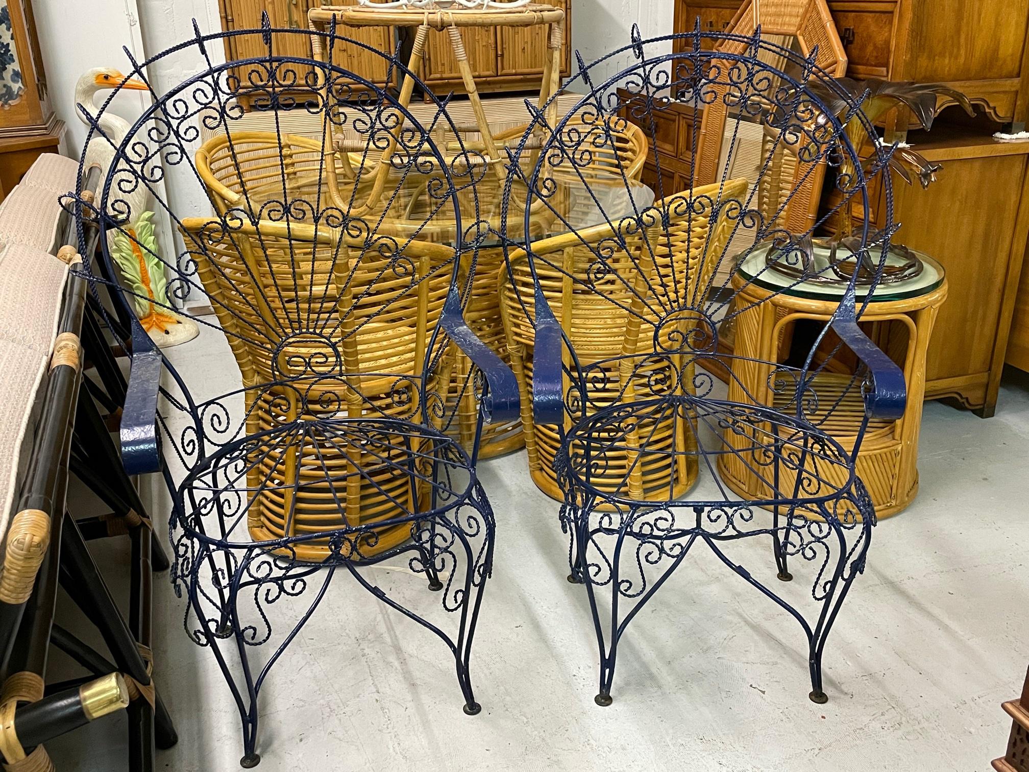 Set of two wrought iron peacock garden chairs by Salterini feature large fan backs and a twisted wire frame. Decorative scroll detailing in this Victorian style chair. Good condition with imperfections consistent with age, including some paint