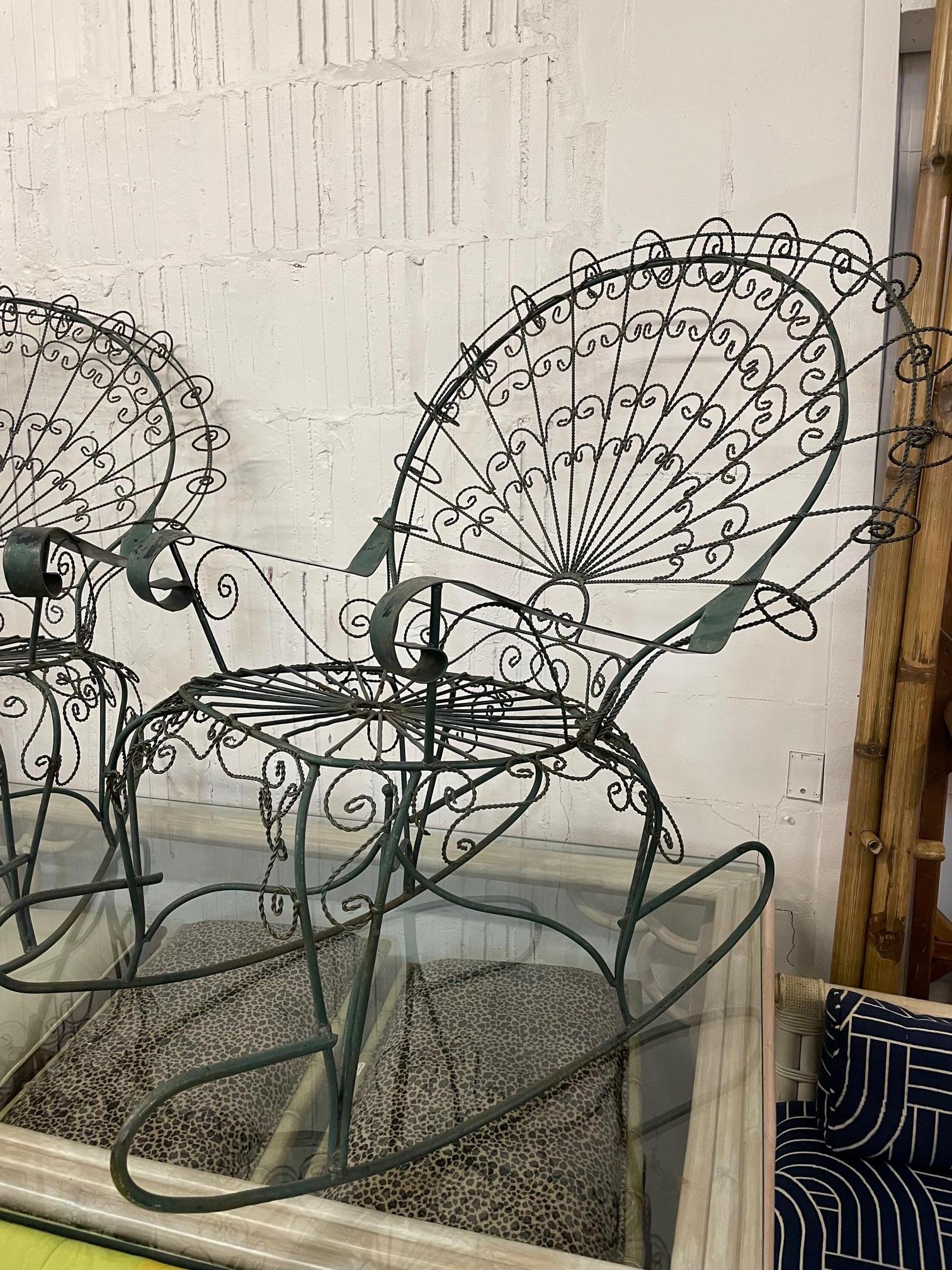 Set of two wrought iron peacock garden chairs attributed to Salterini (not marked) feature large fan backs and a twisted wire frame. Decorative scroll detailing in this Victorian style chair. Good condition with imperfections consistent with age.