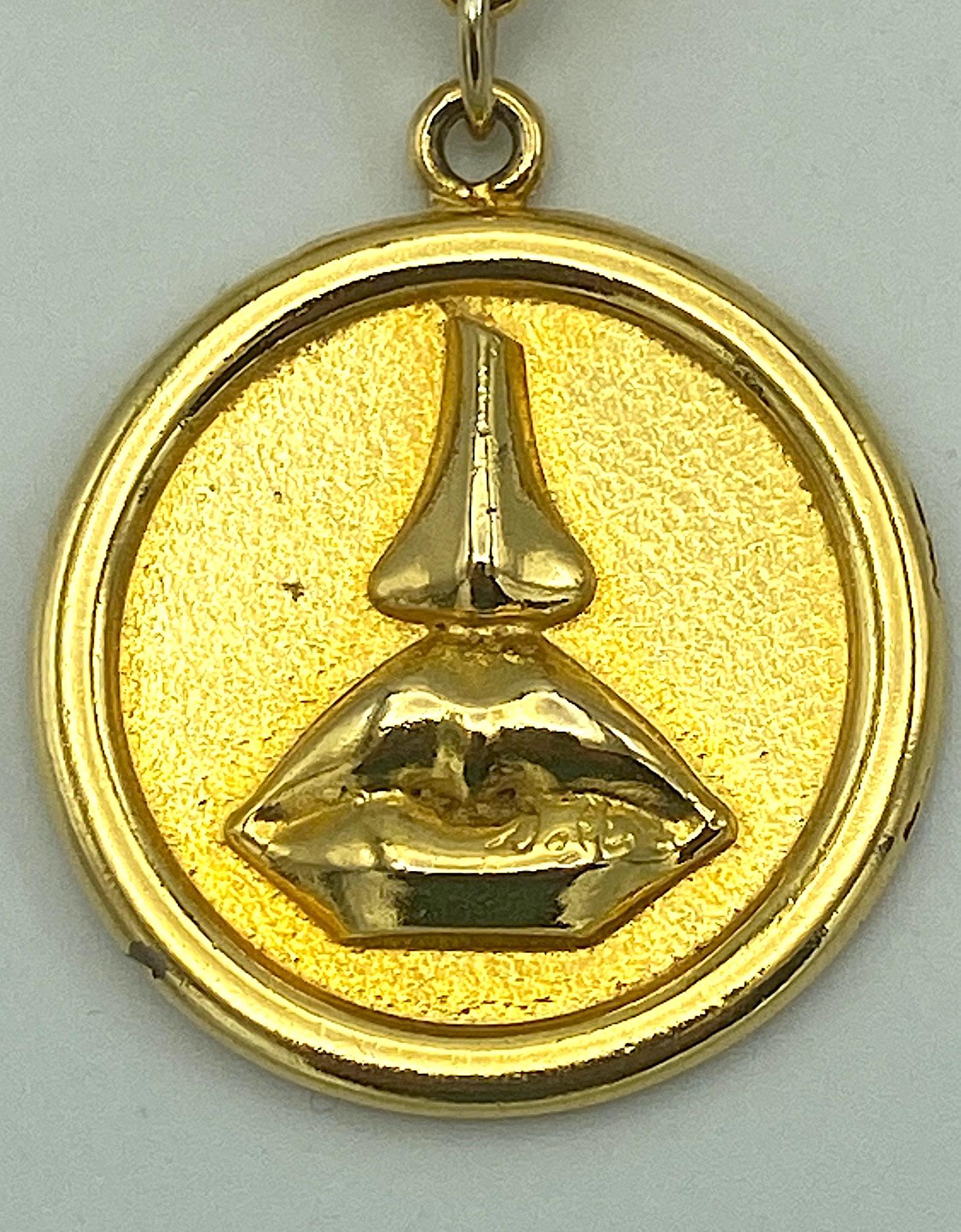 The elegant gold plate brooch was produced in the 1980s as a promotion with the release of Salvator Dali's first fragrance, Aphrodite. The top bar, 2.75 inches length, has an Art Deco design and a pin back. Suspended from it is 1.5 inch diameter