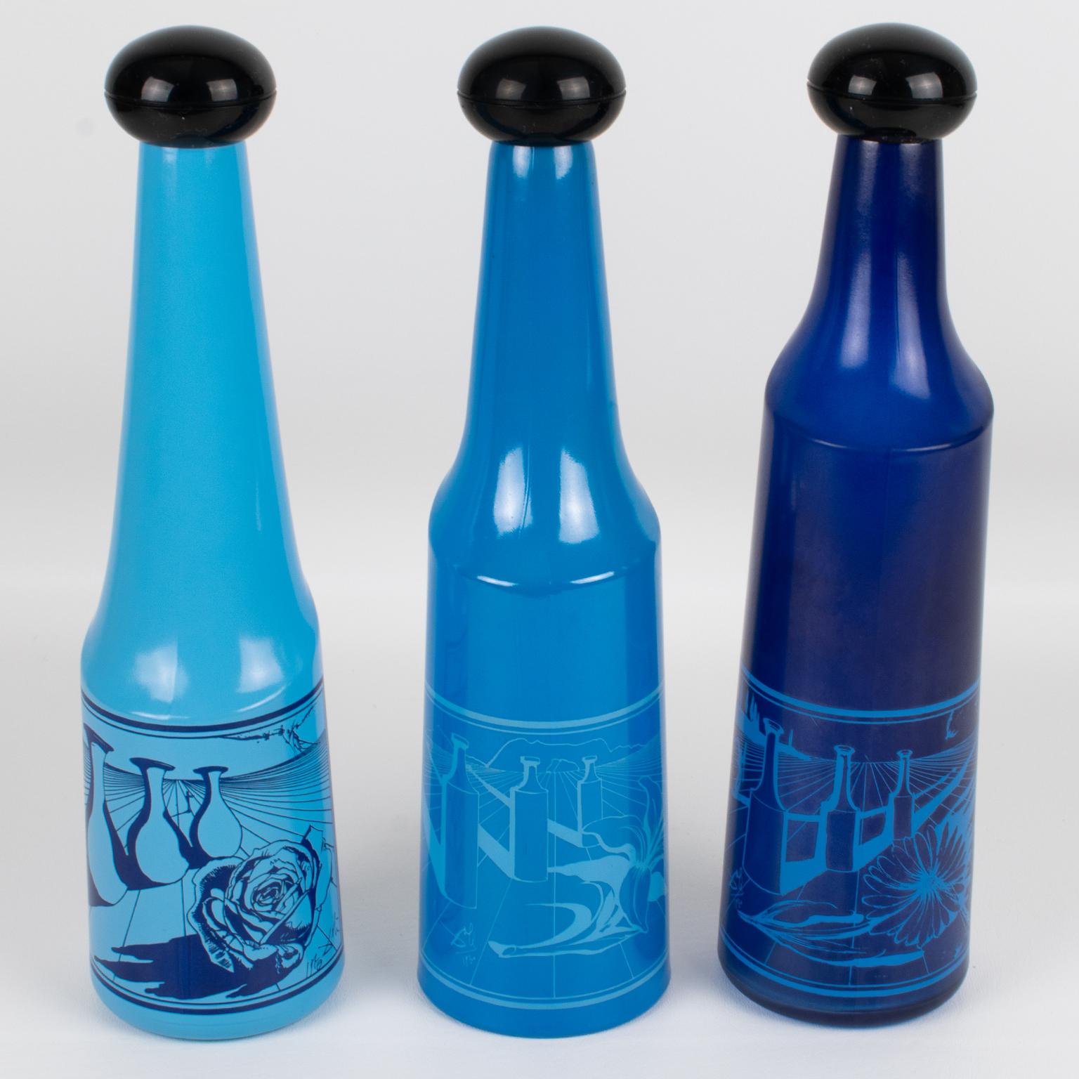 This stunning set of three colored glass bottles was designed by Salvador Dali (1904 - 1989) for Rosso Antico, Ltd, Italy, in the 1970s. Those geometric barware liquor bottles are in an assorted blue hue with Dali's surrealistic designs in blue