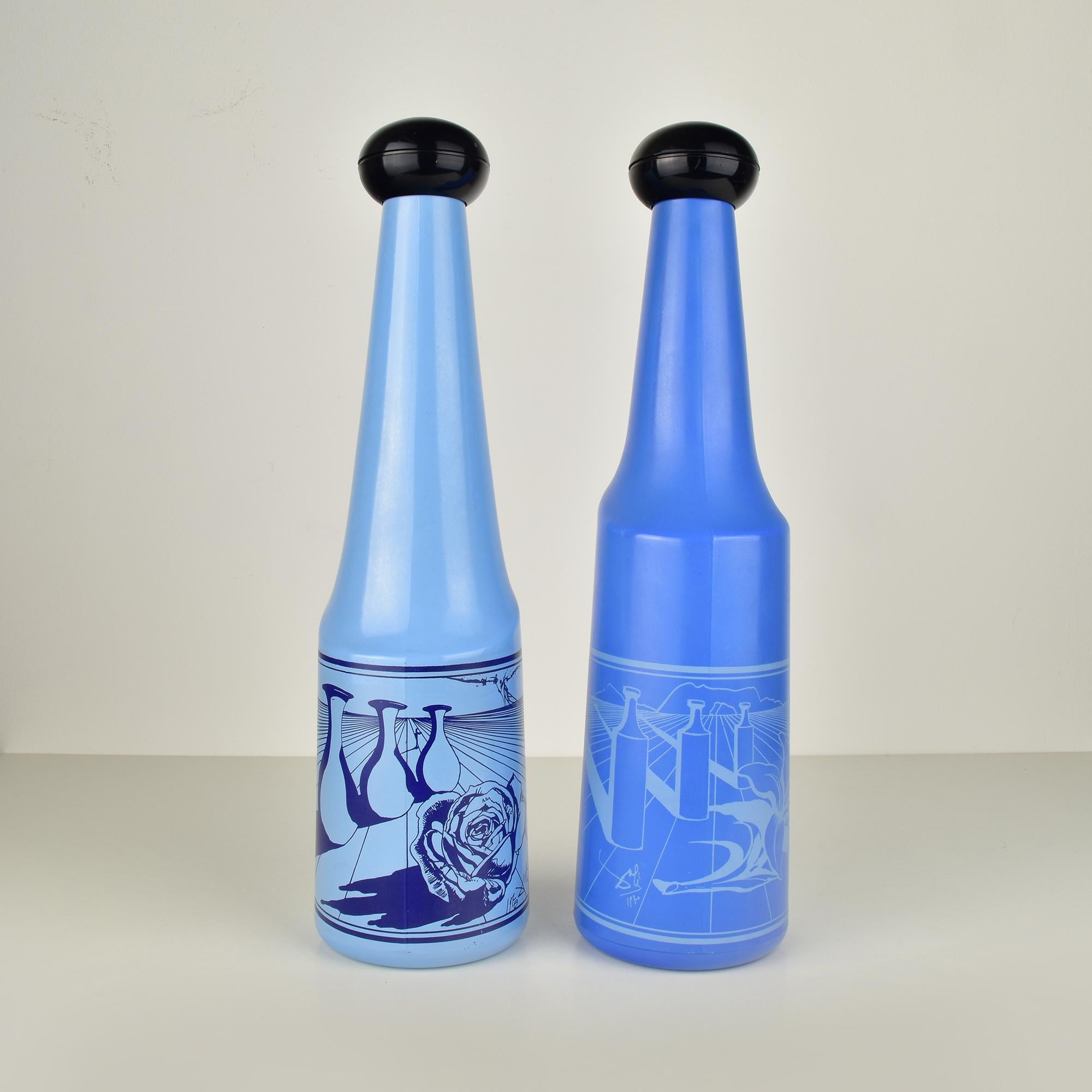 This Salvador Dalí for Rosso Antico Blue Glass Barware Bottles Set, produced in Italy during the 1970s, combines artistic flair with functional barware. The set includes two bottles with elongated, conical shapes tapering toward the top, made blue