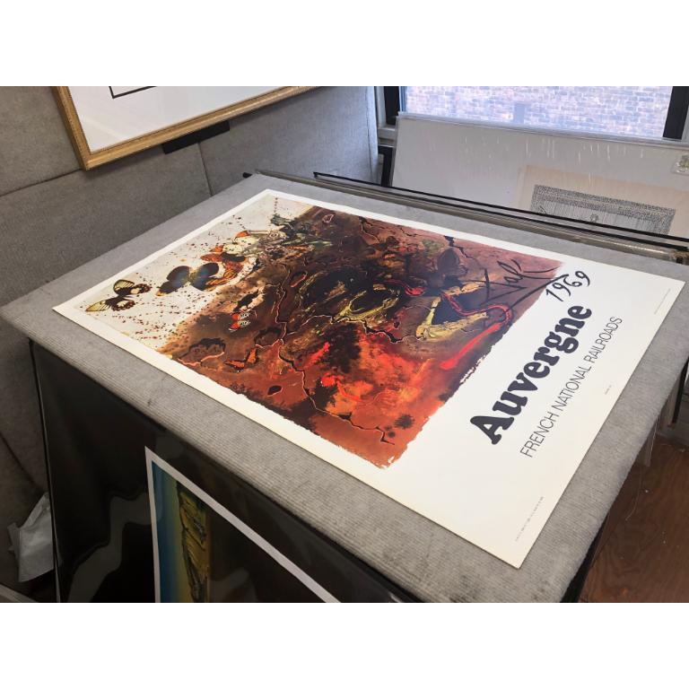 The Auvergne poster by Salvador Dalí is part of a series he created in 1970 for the French National Railway Company (SNCF) to promote travel to various regions of France. This particular poster captures the essence of Auvergne, a region known for