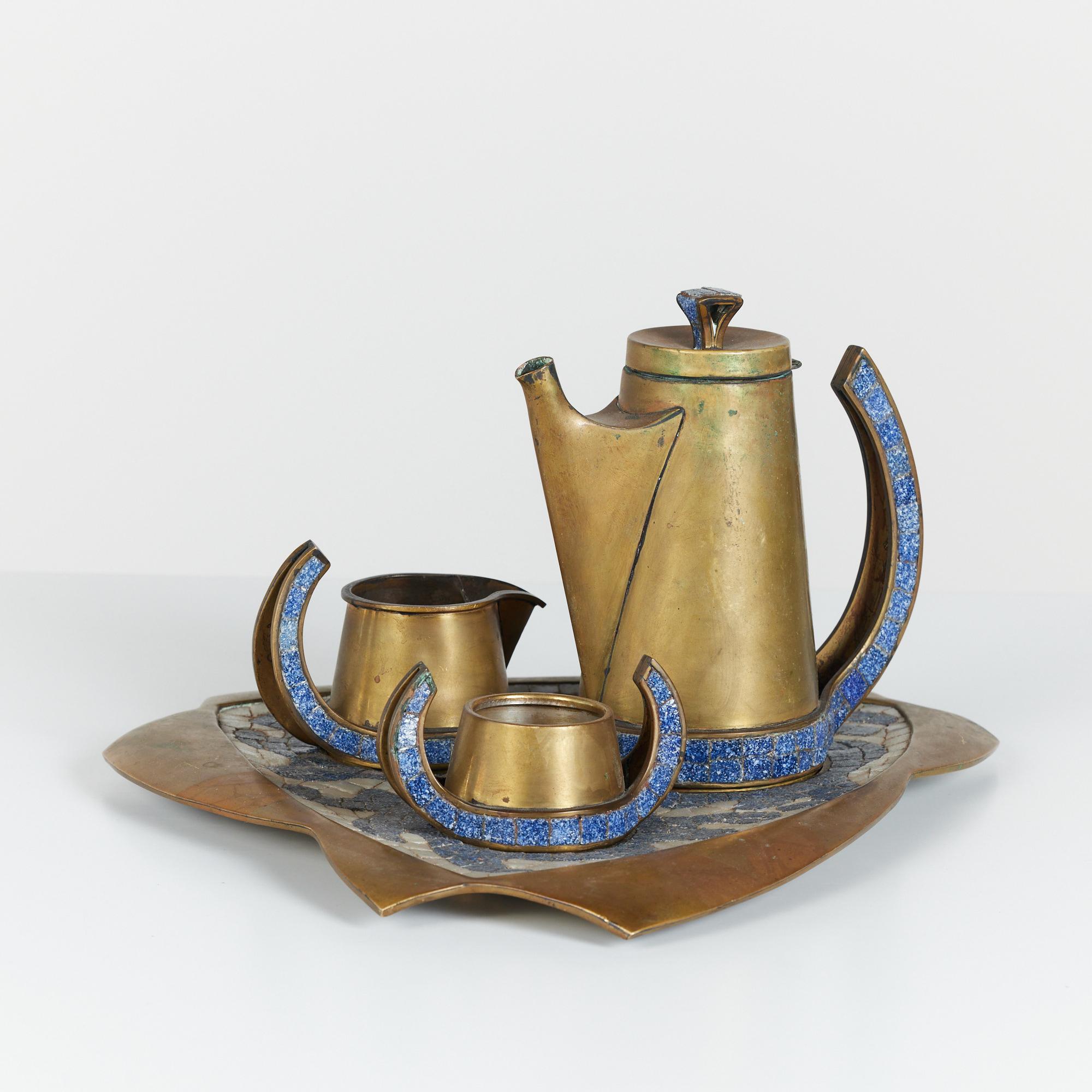 A four piece handwrought midcentury brass tea service set by Salvador Teran, c.1950s Mexico. The set includes a lidded brass teapot with creamer and sugar pot all with curved handles featuring square blue speckled tile mosaic inlay. The pieces sit