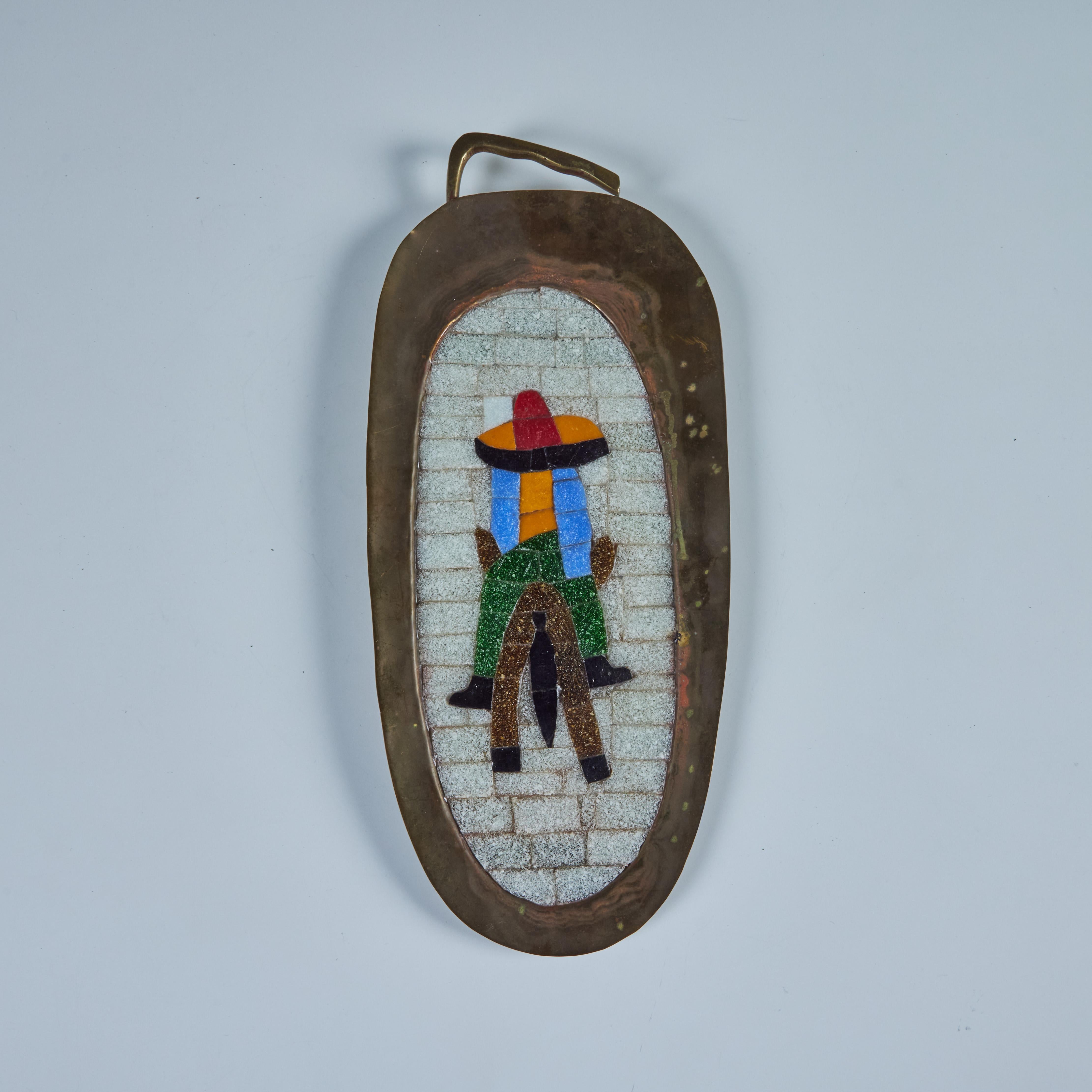 Ovaler, handgeschmiedeter Messing-Wandbehang im Stil von Salvador Teran, ca. 1950er Jahre, Mexiko. Das Tablett zeigt die Mosaikeinlage eines Mannes, der auf einem Esel reitet und einen Sombrero trägt.

Abmessungen
15