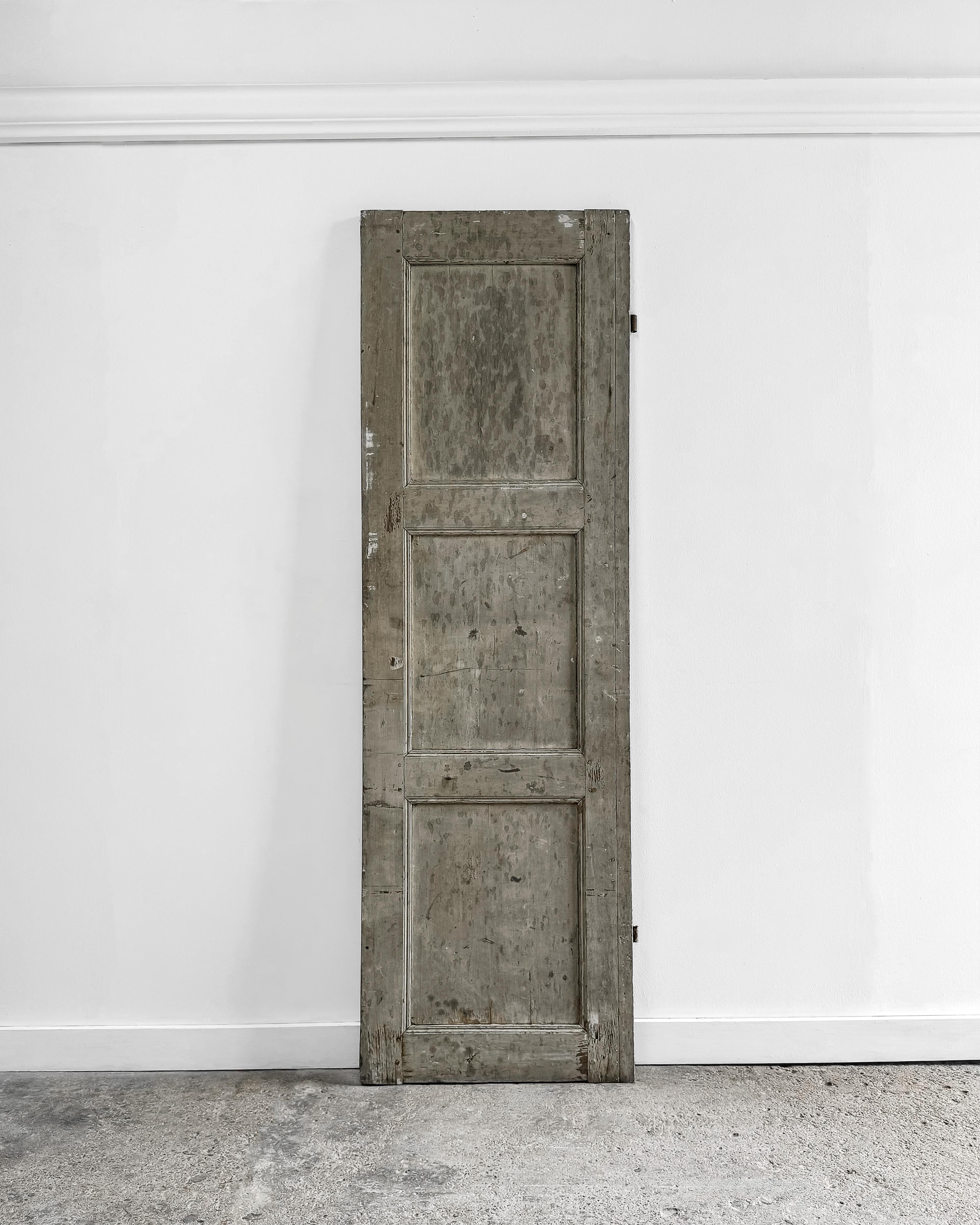 A reclaimed French shutter with grooved beveled trim detailing and its original sage-gray paint. This charming piece can be installed to enclose a cupboard, providing a unique and stylish touch to your storage solutions. Alternatively, use it as a