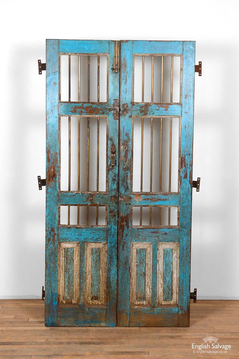 Antique salvaged Jali doors from India. Worn light blue paint with white detail to the lower fielded panels gives the doors a weathered appearance and a beautiful patina. Each door has three rusty metal hinges to the outer edge and metal bars to the
