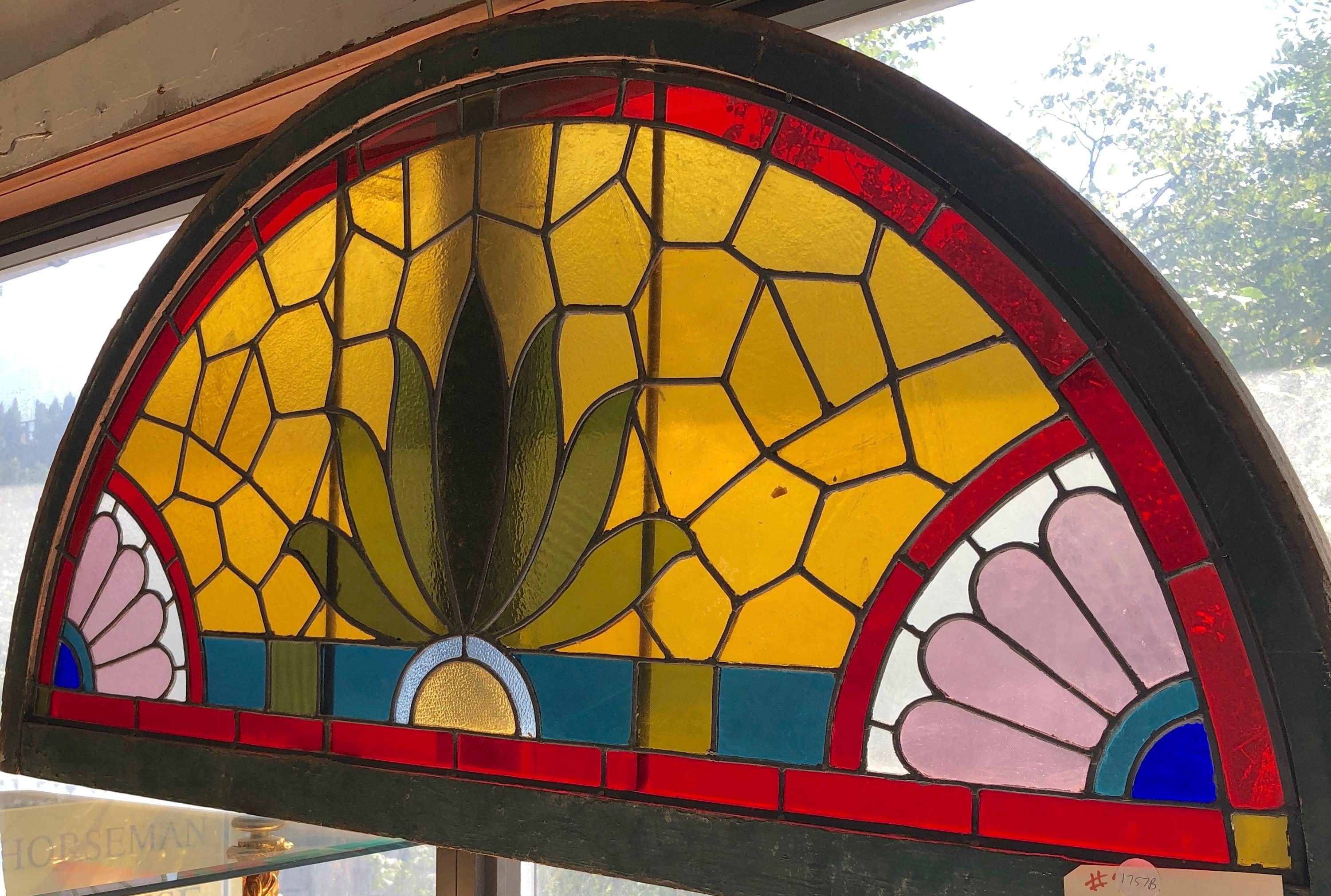 Large stained glass transom window with vibrant colored glass. This window gives full privacy with no clear glass, and a wonderful leaded design to enhance your front door.
Currently housed in a wooden frame - the overall dimensions are for the