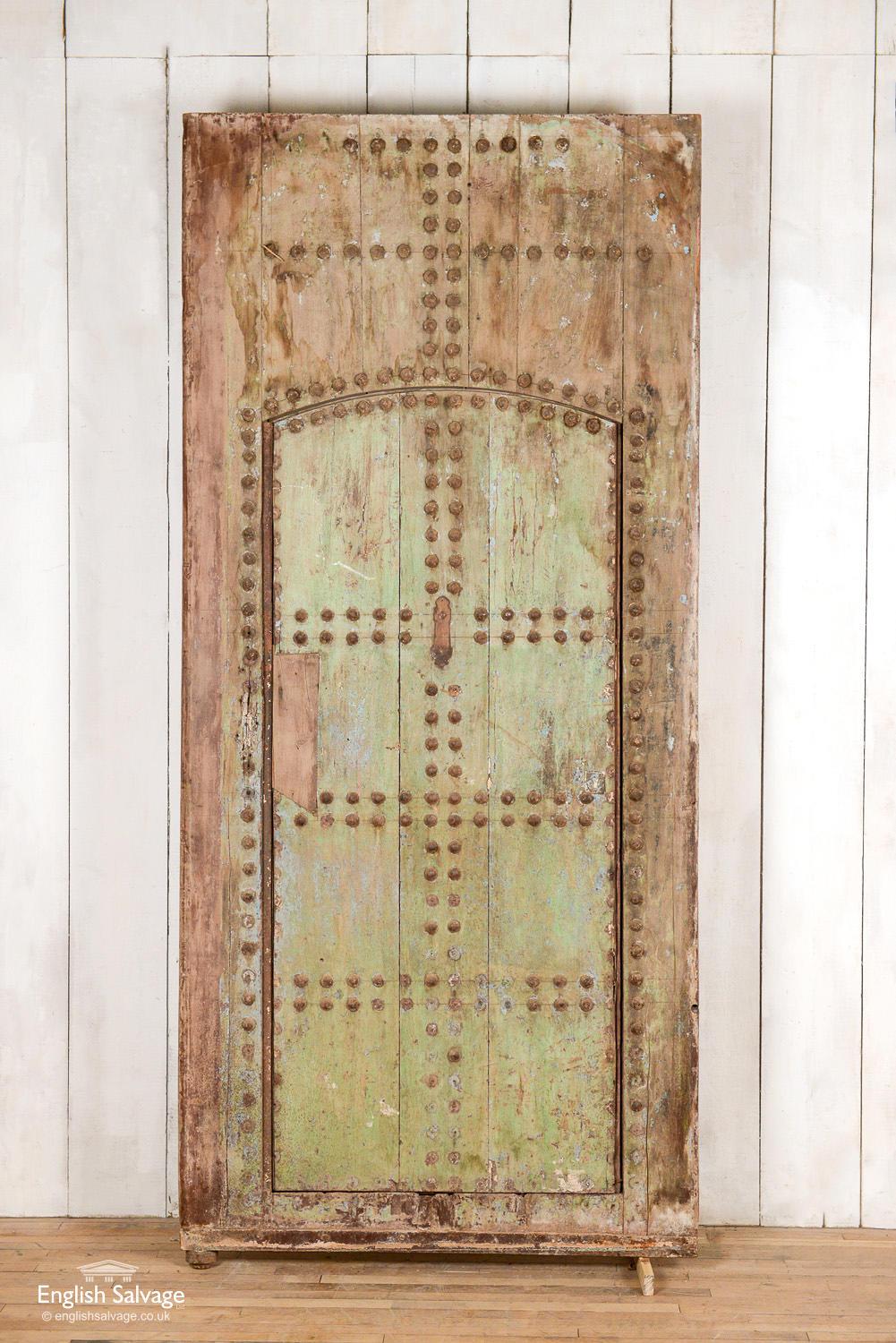 Old hardwood studded door in frame from Morocco. Lovely old paint patina and thick framed back to the door. Splits and scuffs commensurate with age.