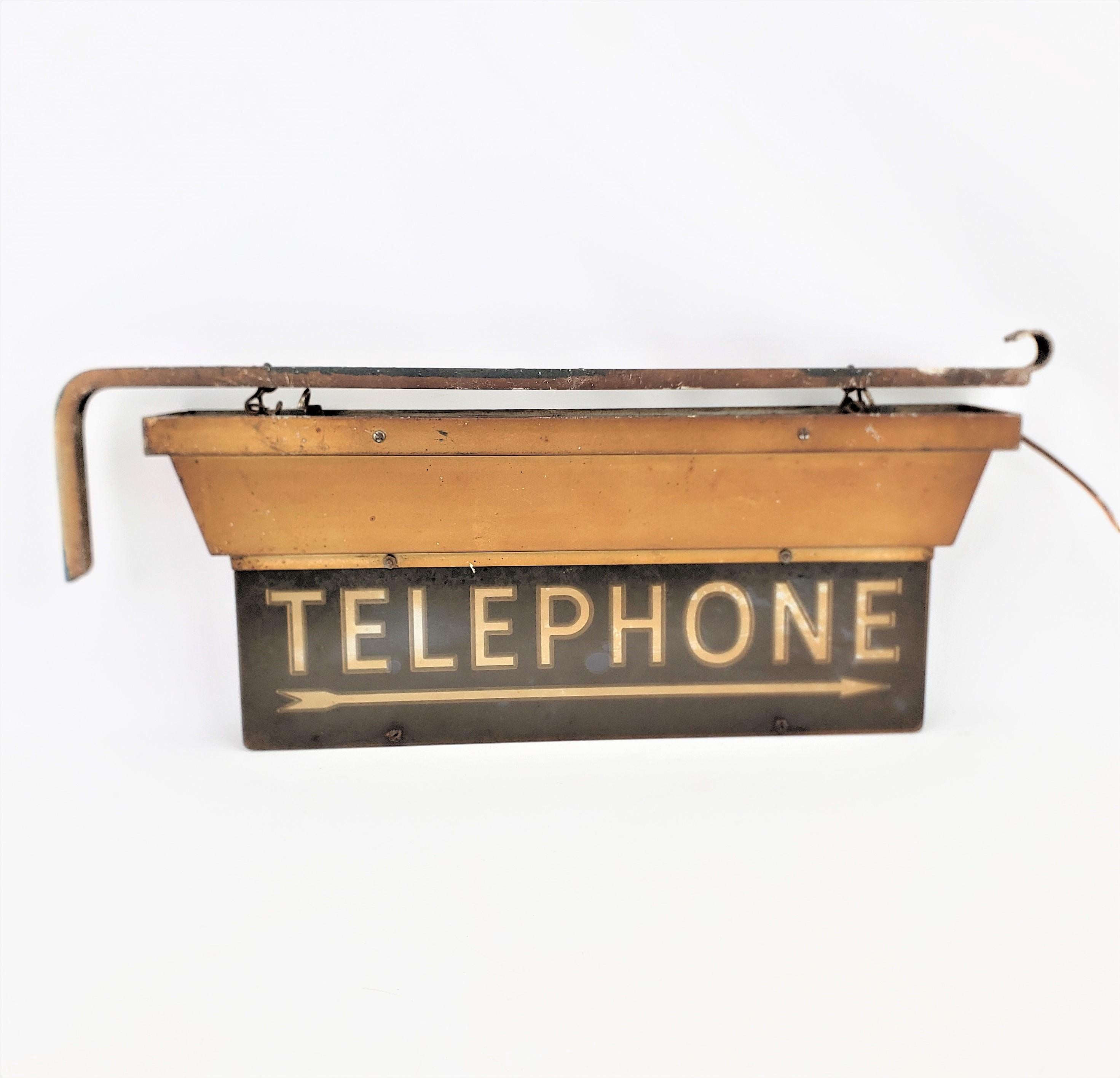 This salvaged commercial lighted telephone sign is signed by an unknown maker, and originated from Canada, dating to approximately 1960 and done in the period Mid-Century style. The base is made of metal which has a gold finish, and the sign itself