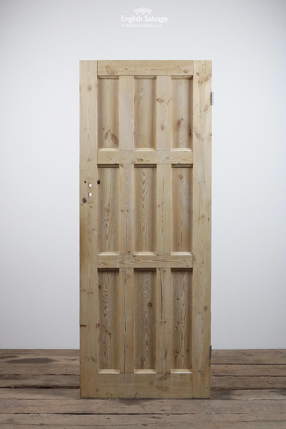 Salvaged stripped pine door with four nine vertical panels and two hinges. Handle, lock and nail holes plus a few bumps to edges.