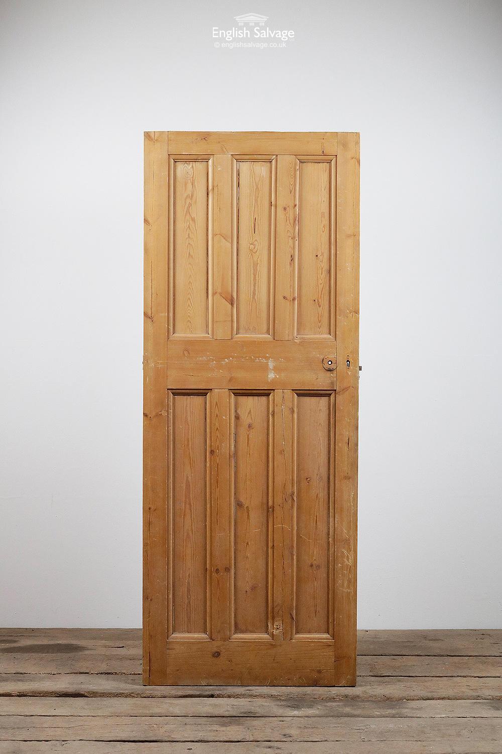 Salvaged stripped pine door with three over three vertical panels. Handle, lock and nail holes plus a few scuffs to the bottom rail.
  