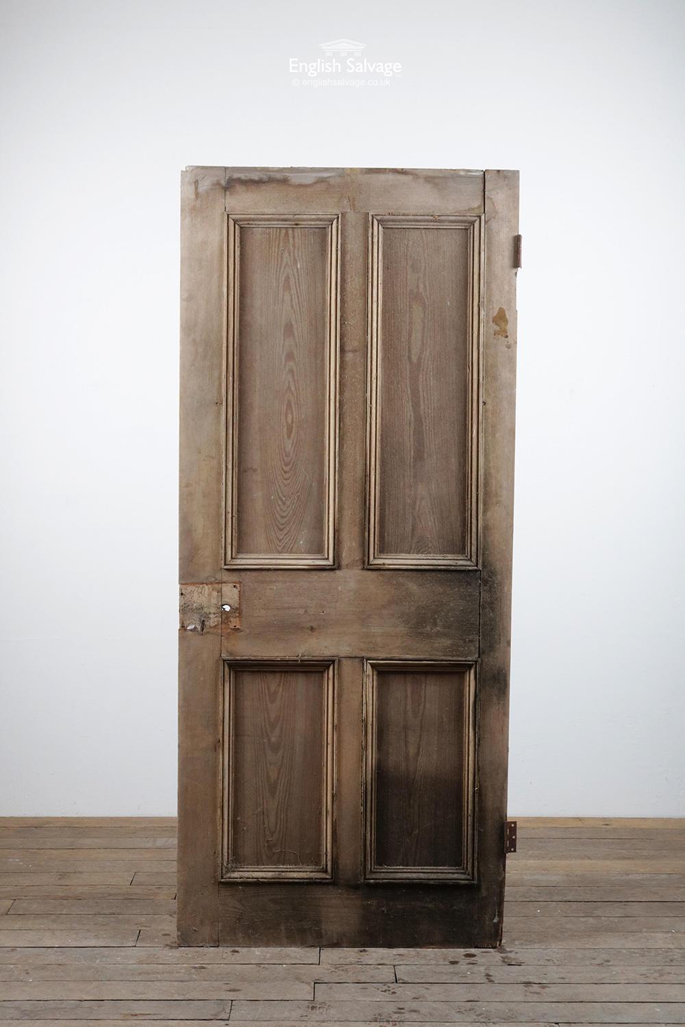 Four panel reclaimed pine door. Raised and fielded panels to the one side, beaded to the other. A low and wide door, cut down at the hinge side. Slight separation, heavy staining to the one side in particular. Old lock holes, two hinges.