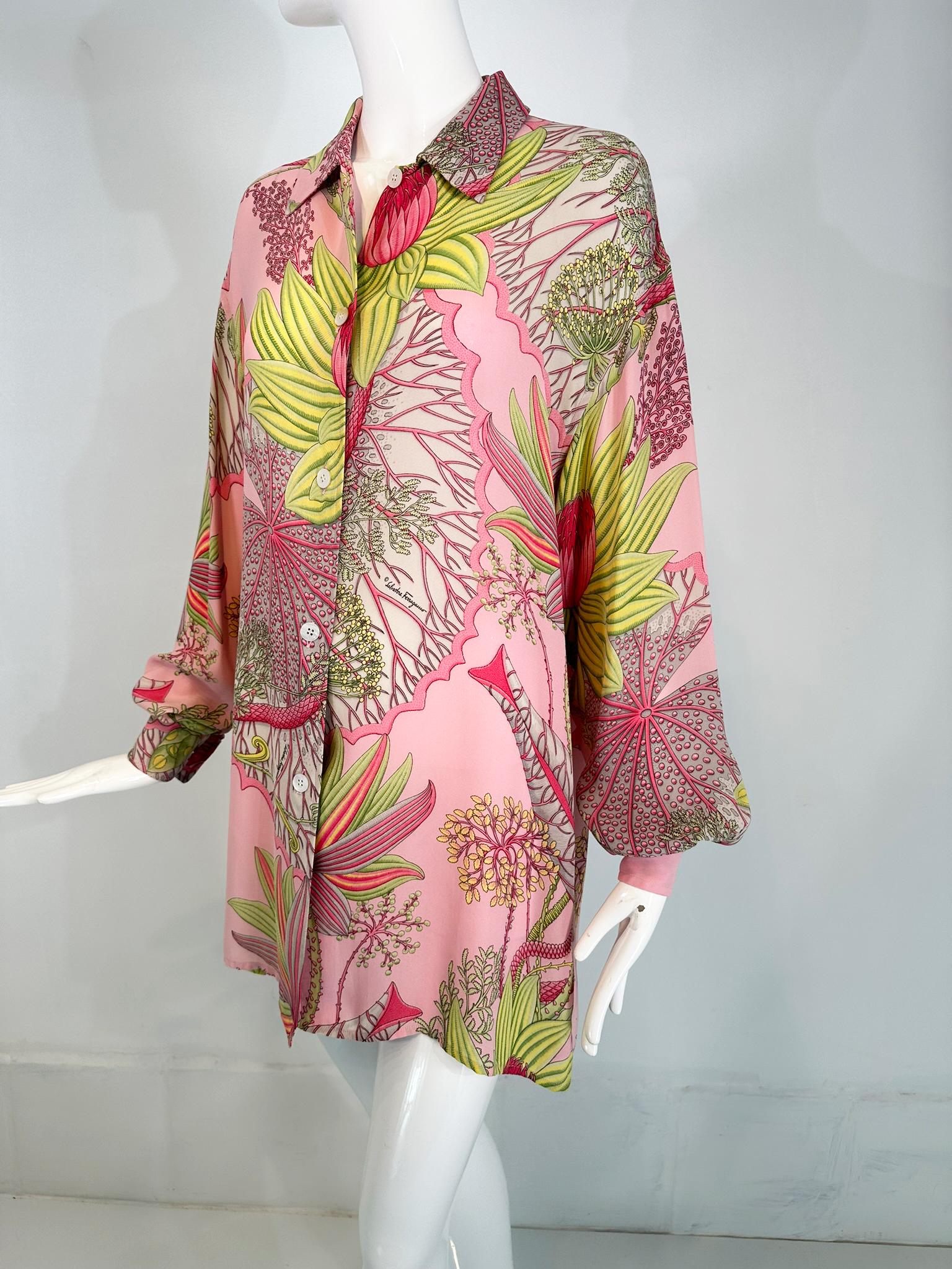 Salvatore Ferragamo 1990s silk crepe tropical foliage oversize blouse tunic. This beautiful blouse is done with a pink ground and an assortment of tropical foliage throughout. Long sleeve blouse with button cuffs. Small collar, Button front blouse