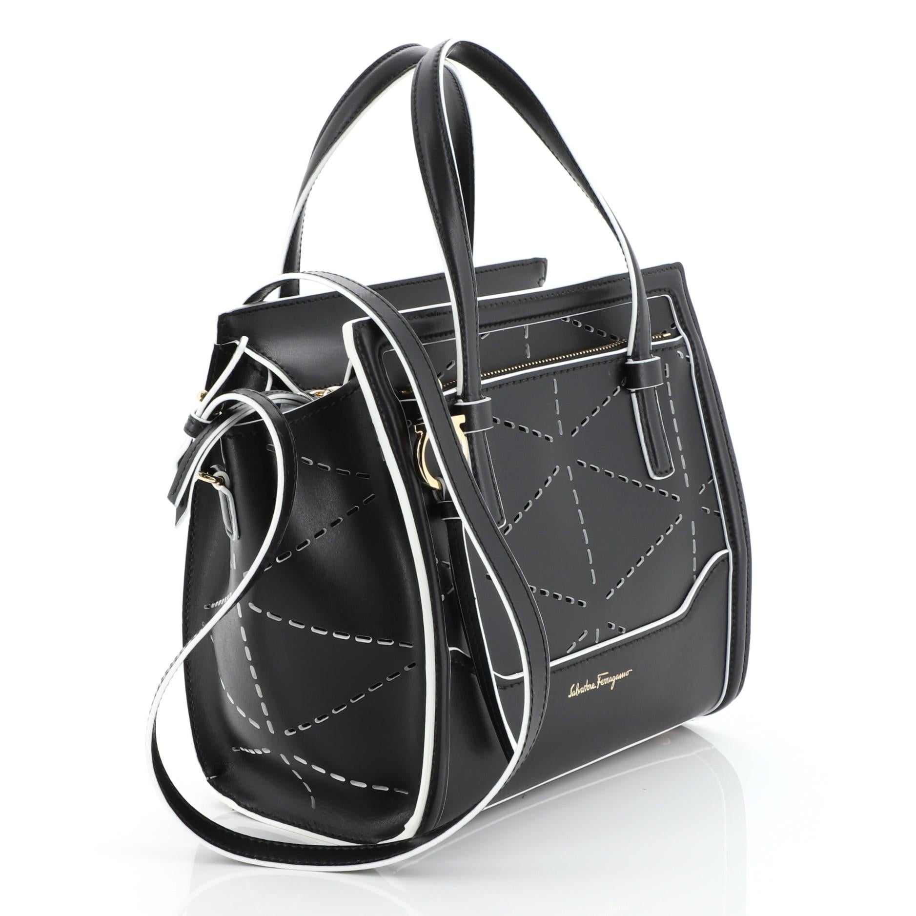 This Salvatore Ferragamo Amy Tote Perforated Leather Mini, crafted from black perforated leather, features dual flat handles, exterior front zip pocket with Gancio charm zip pull, and gold-tone hardware. Its zip closure opens to a black leather