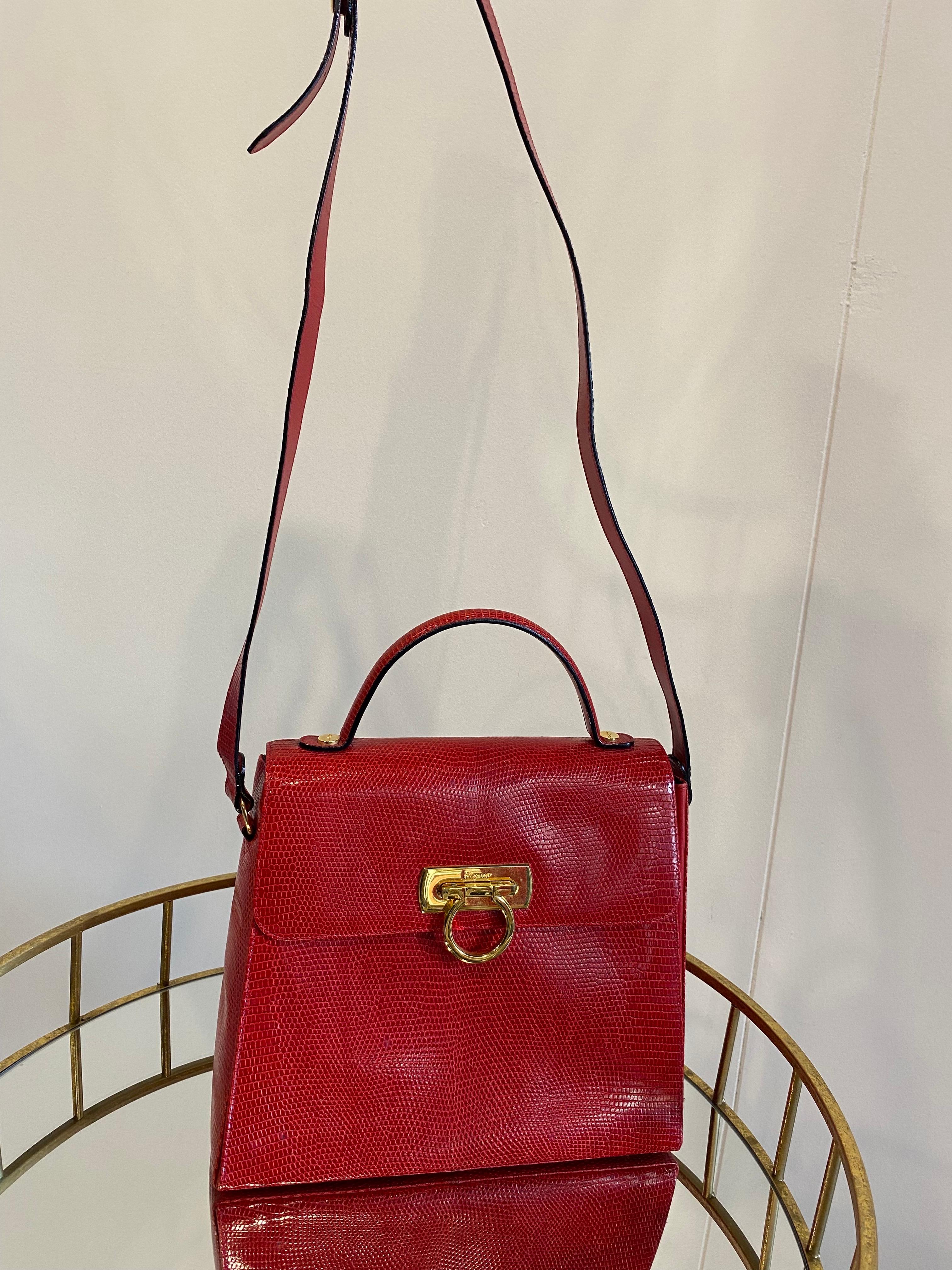 Salvatore Ferragamo bag in red lizard. It is equipped with both a handle and a shoulder strap. Golden hardware. The interior is in black leather with two compartments, one of which has a small zipped pocket. The bag is in excellent condition, with