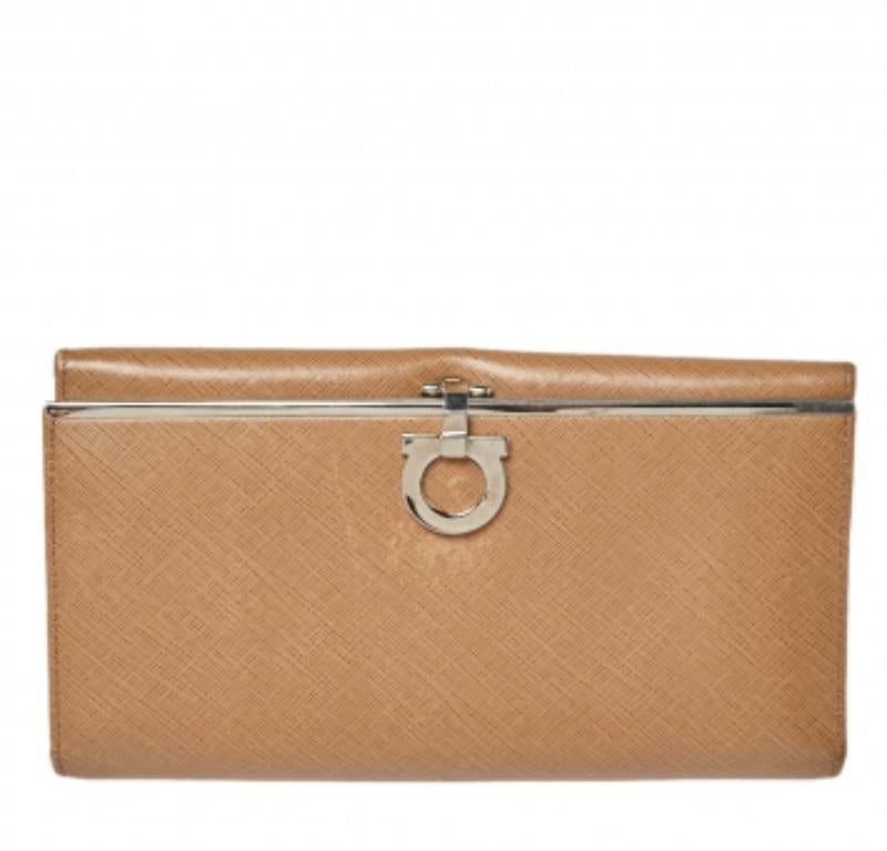 Crafted from leather, this continental wallet from Salvatore Ferragamo carries the signature Gancini motif on the front flap and a beige hue. The flap opens to a functional interior equipped with multiple slots and a zipped compartment to carry your