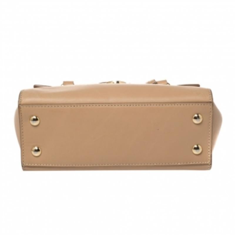 This Mara satchel from Salvatore Ferragamo is an outstanding bag that comes crafted from beige leather and has dual top handles, a detachable shoulder strap, and a gold-tone signature ganchini lock on the front. It boasts a leather-lined interior
