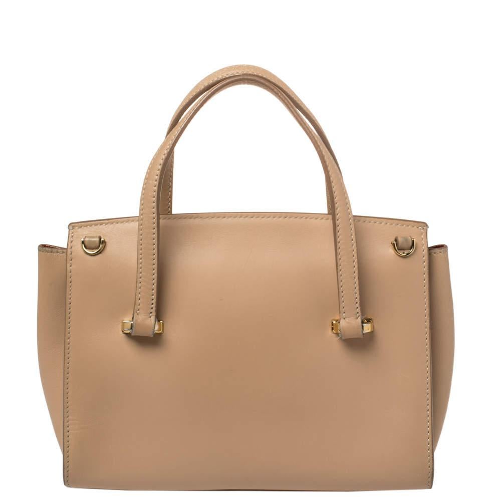 This Mara satchel from Salvatore Ferragamo is an outstanding bag that comes crafted from beige leather and has dual top handles, a detachable shoulder strap, and a gold-tone signature ganchini lock on the front. It boasts a leather-lined interior