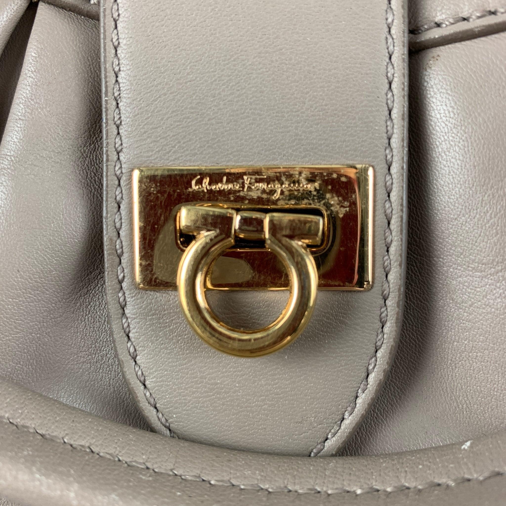 SALVATORE FERRAGAMO comes in a beige leather featuring a medium size, two inner zipper pocket, inner compartment, and gold tone hardware. Made in Italy.Very Good Pre-Owned Condition. Moderate wear.  

Marked:   AU-21/D227 

Measurements: 
  Length: