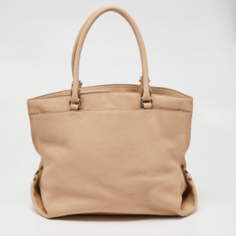 Ce fourre-tout Dotty de la maison Salvatore Ferragamo est super classe et fonctionnel, parfait pour un usage quotidien. L'extérieur est en cuir beige grainé et le devant est orné d'un logo argenté. Il est muni de deux poignées bien dessinées.