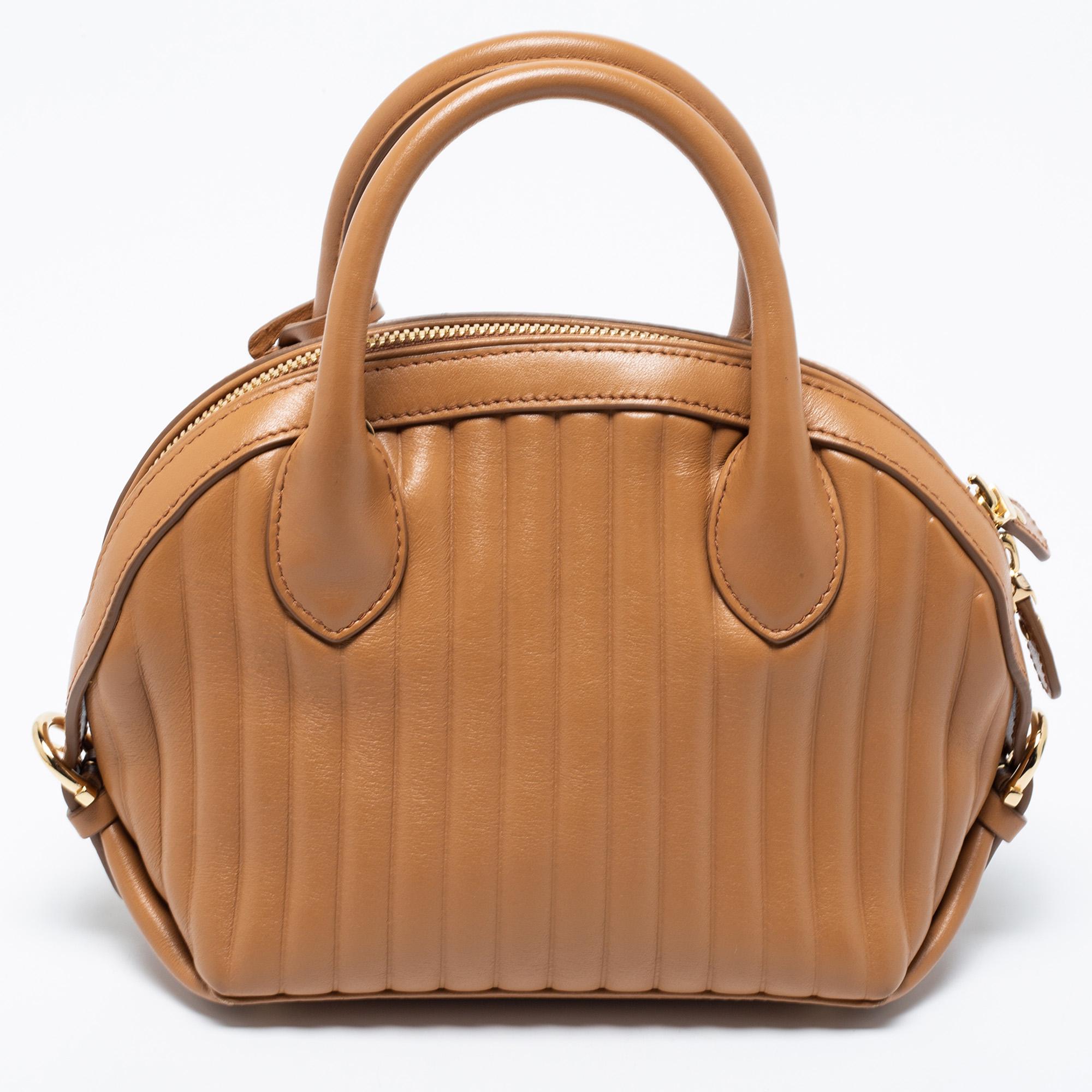 Salvatore Ferragamo's Fiamma satchel is an elegant style that aims to offer an elevating finish. Crafted using beige quilted leather, the bag is designed with a gold-tone lock on the front. It comes with dual top handles, an optional strap, and a