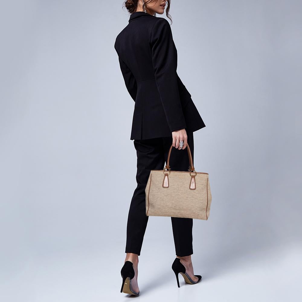 This Ferragamo tote makes an ultimate style statement for all the trend-savvy women out there. It is crafted from beige canvas and tan leather and styled with dual top handles. It opens to a canvas interior that has ample space to accommodate your