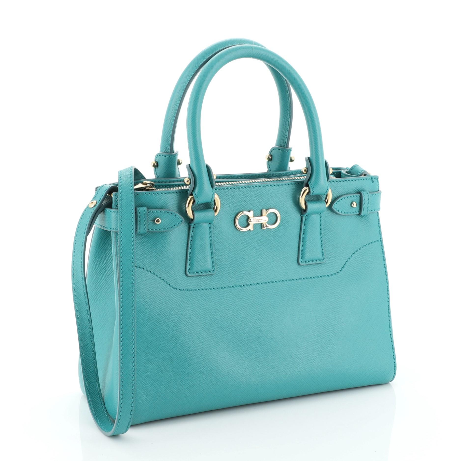 This Salvatore Ferragamo Beky Handbag Saffiano Leather Small, crafted from green saffiano leather, features dual-rolled leather handles, signature Gancini detail at top center, tonal topstitching detail, two exterior side compartments, side snap