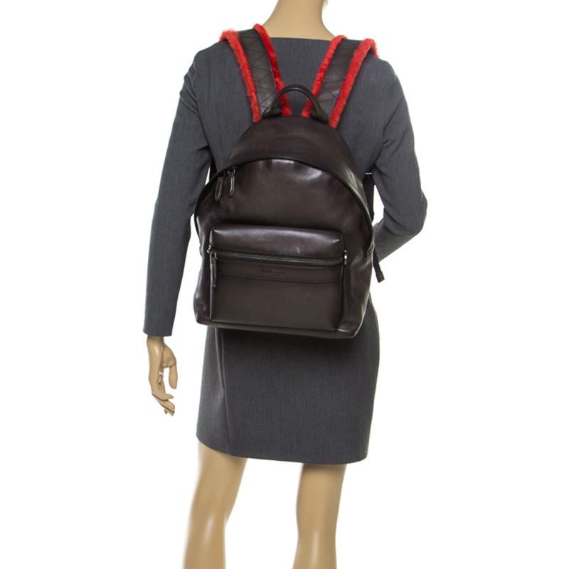 Carry your daily essentials in style with this Firenze backpack from Salvatore Ferragamo. Crafted from leather and fabric it flaunts zippers that reveal a spacious interior, a zip pocket on the front and shoulder straps with fur. This piece comes in