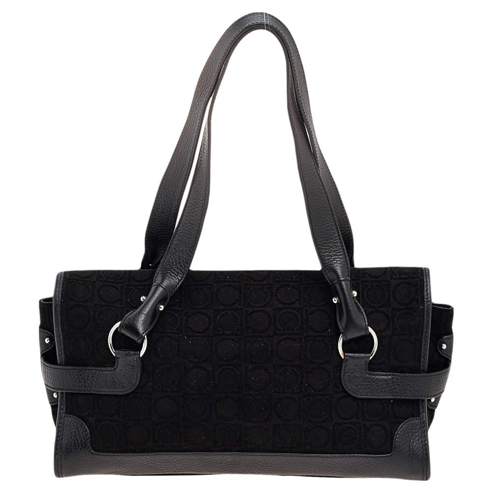 This Salvatore Ferragamo bag features an exterior made of black velvet and leather with silver-toned Gancini detail on the front flap. It carries a spacious fabric-lined interior that will store all your belongings safely. Pair this handbag with