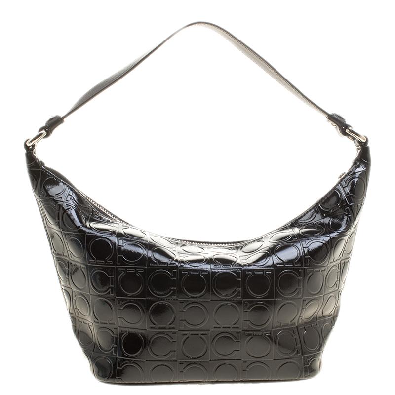 Featuring an angular silhouette, this Salvatore Ferragamo hobo is designed from a black Gancio embossed patent leather body and secured with a top zipper closure. It comes fitted with a shoulder strap and detailed with silver-tone hardware. Carry it