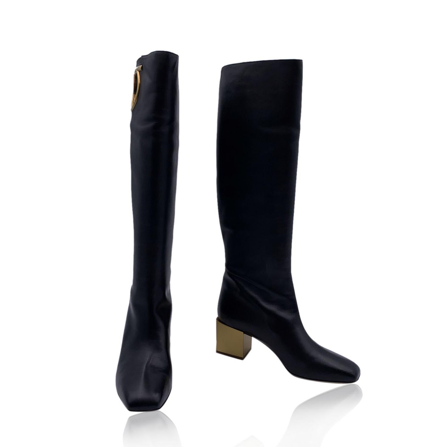 Stunning Salvatore Ferragamo Avio 55 Knee-High Boots. Crafted in black calf leather, they feature square toe, pull-on style and cut-out Gancino detail on the top. Detailed with gold-tone mirrored heels. Leather sole. Heels Height: 2 inches - 5 cm.