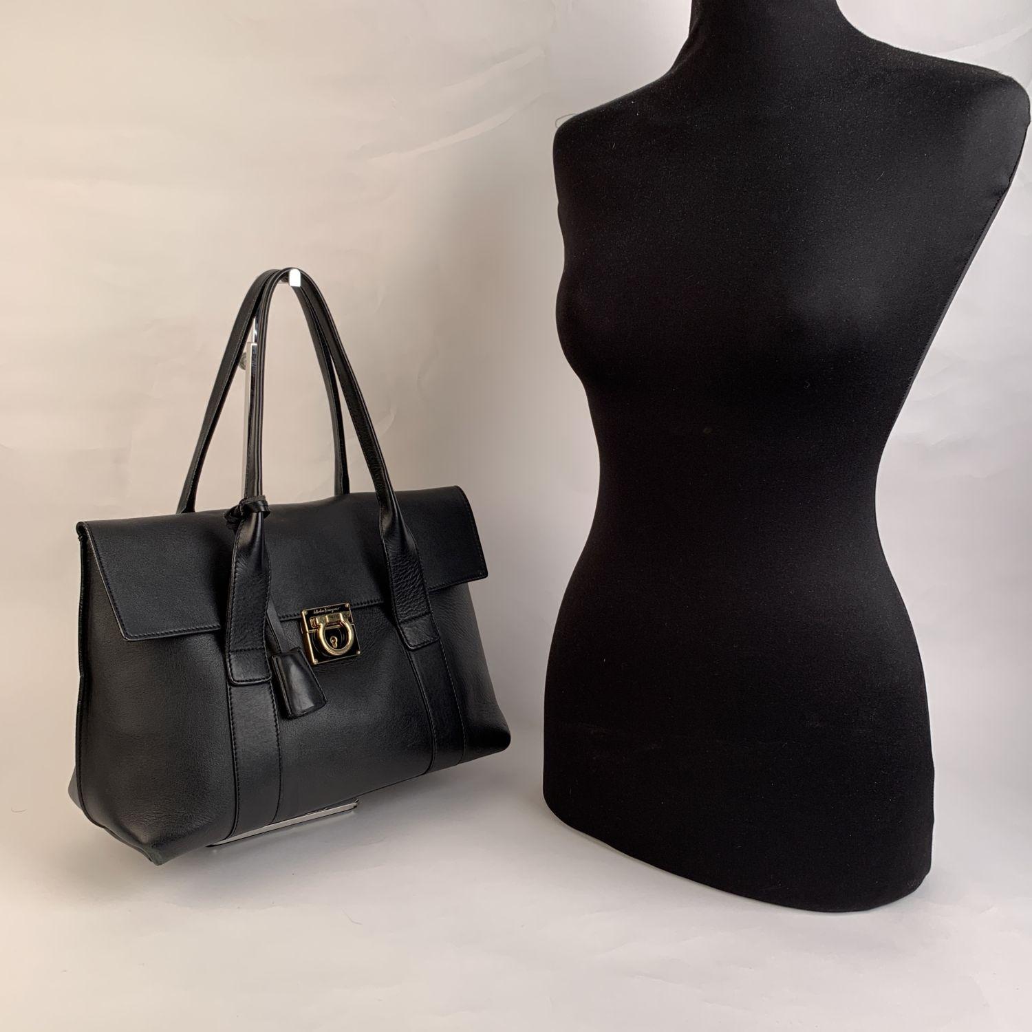 Salvatore Ferragamo black leather 'Sookie' tote bag. It features double handle, flap closure with gold metal Gancini closure. Additional key lock closure (key and leather clochette are included). Interior zip pouch inside. 'Salvatore Ferragamo -