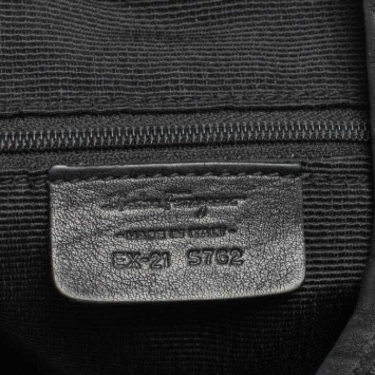 The relaxed silhouette and the monogram canvas construction bring out the appeal of this Salvatore Ferragamo black bag. It features a leather top handle and a zip closure that leads to a nylon-lined interior.