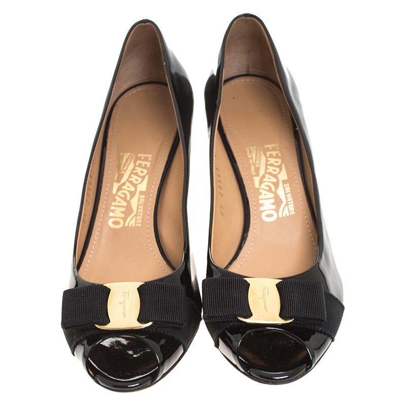 Feel the admiring glances coming your way whenever you step out in this pair of gorgeous pumps from Salvatore Ferragamo. They've been crafted from black patent leather and styled with signature bows on the uppers. The pumps carry peep toes and they