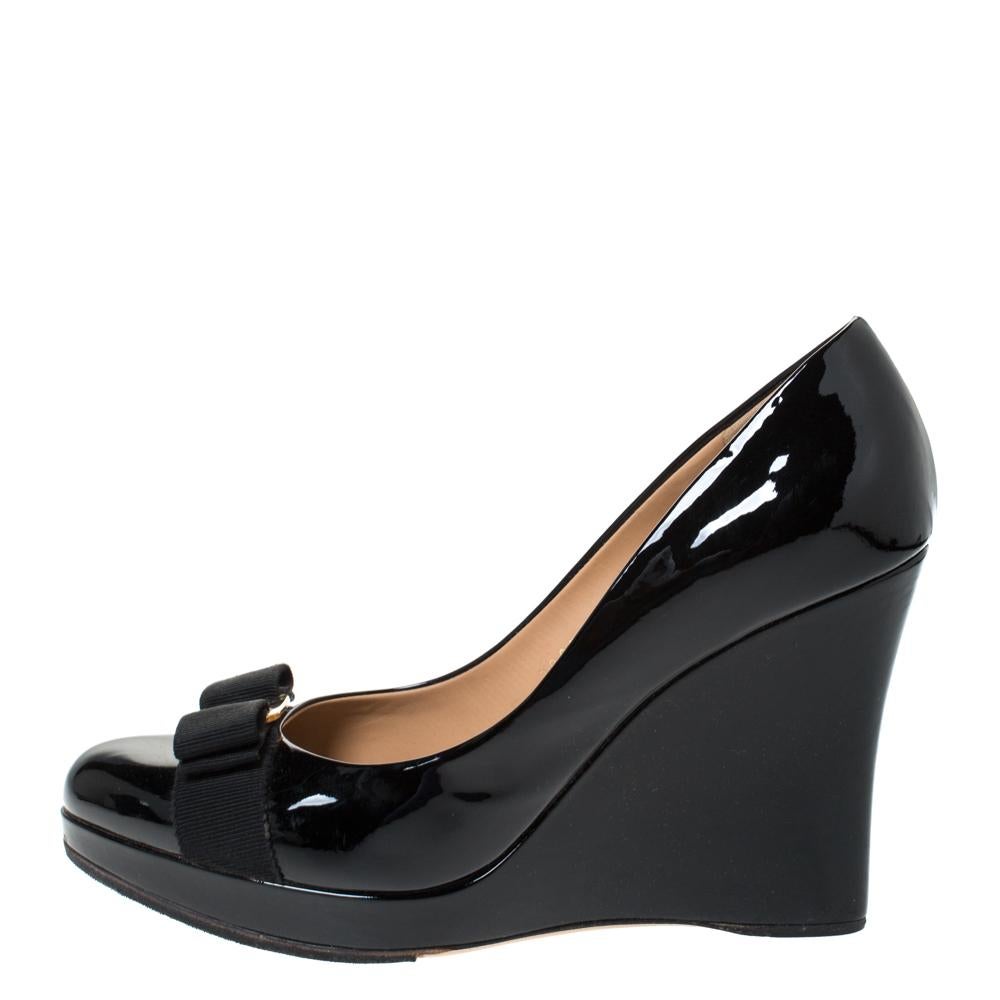 Todo armario merece un par de zapatos de salón clásicos, ¡y qué mejor que estos espléndidos de Salvatore Ferragamo! Estos zapatos de salón con plataforma negros están fabricados en charol y decorados con el característico lazo de grosgrain y