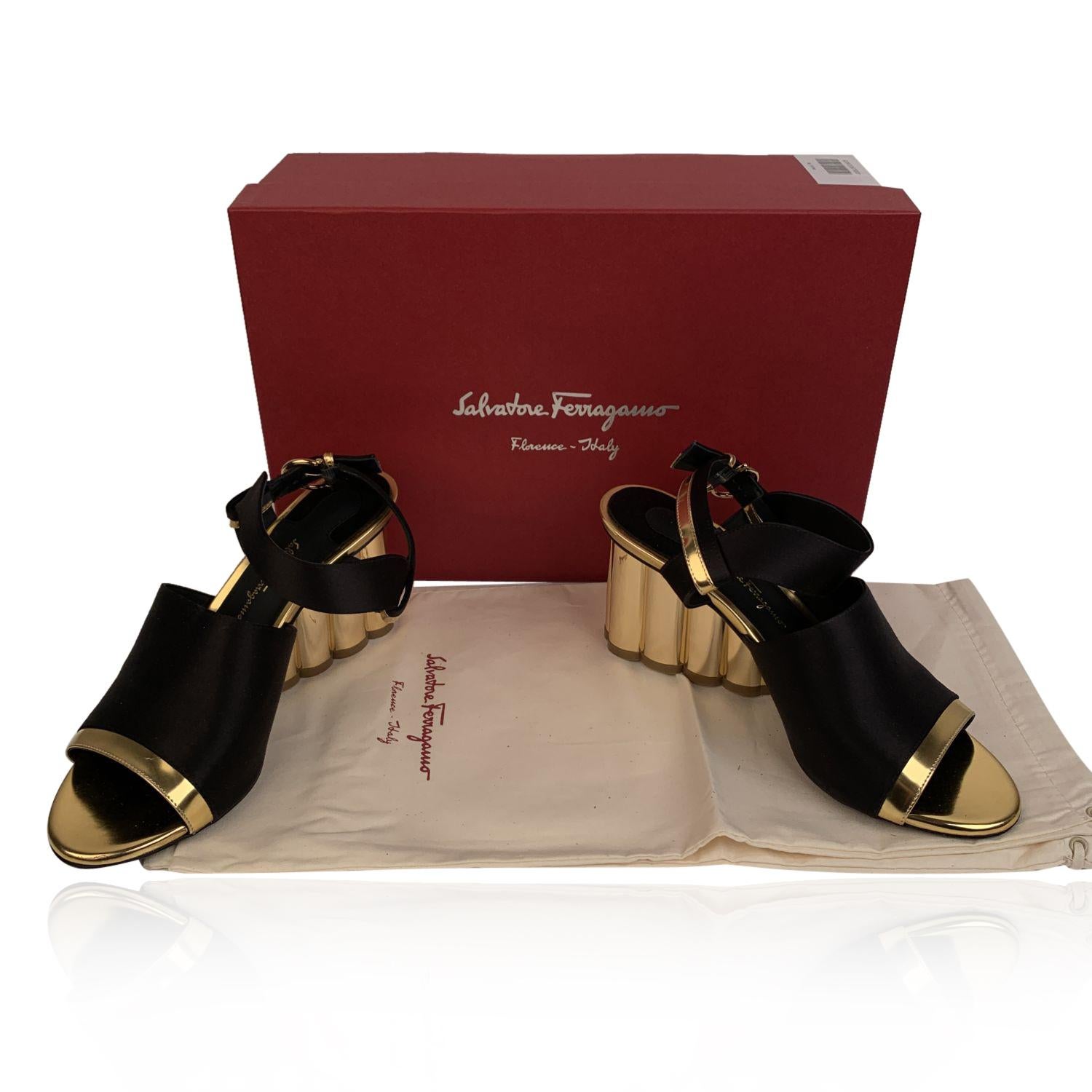 Elegant Salvatore Ferragamo 'Greci 70' heeled sandals. Crafted in black satin with shiny gold metal leather accents. They feature peep toe, slingback design and buckle closure on the ankle. Gold metal scalloped block heels. Heels Height: 2.75 inches