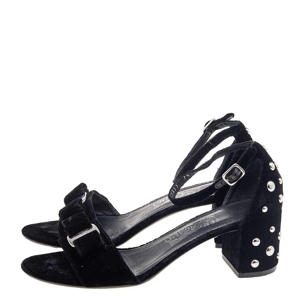 Exude class and perfection as you walk in these sandals from Salvatore Ferragamo. They are crafted using black velvet. They flaunt open-toes, an ankle strap, and studded block heels. Silver-tone hardware is used to adorn their silhouette. Make a