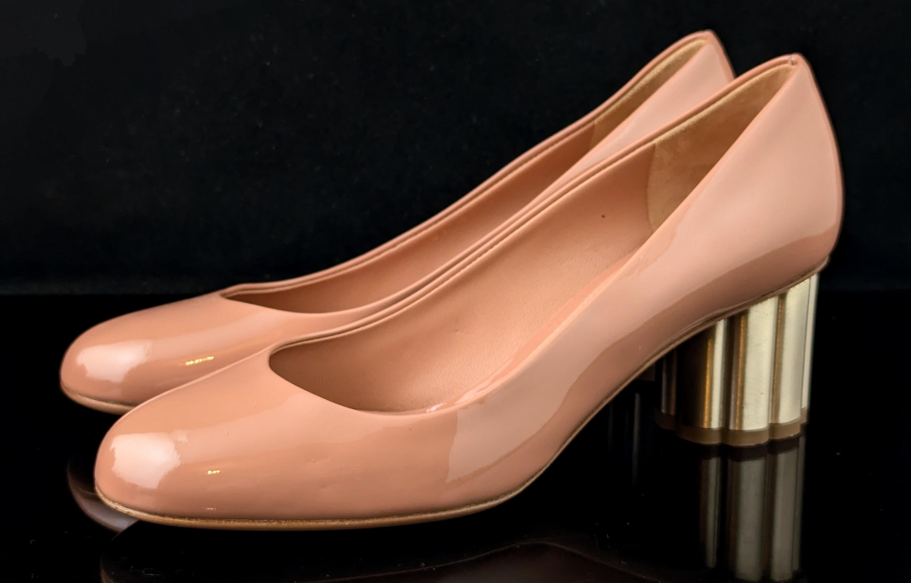 A gorgeous pair of Salvatore Ferragamo blush pink heels.

Patent leather in a warm blush pink colour, they are a court style shoe with a lovely chunky scalloped mid heel in metallic gold.

The gold and the shape of the heel really gives these shoes