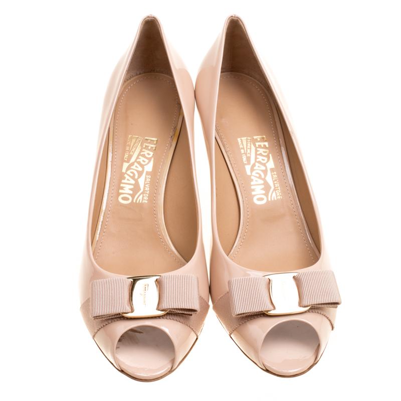 You're all set to make others blush and shine brighter than the sun in these ethereal pumps from Salvatore Ferragamo! The pink pumps are crafted from patent leather and feature a peep-toe silhouette. They flaunt the signature grosgrain bow detailing