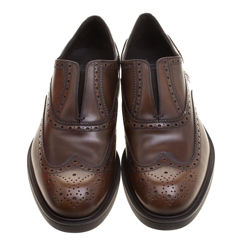 These loafers from Salvatore Ferragamo are sure to make you look suave, smart and very fashionable. Crafted with skill from brogue leather, they flaunt a neat brown shade and a slip-on style. With tough soles for maximum grip and comfort, these