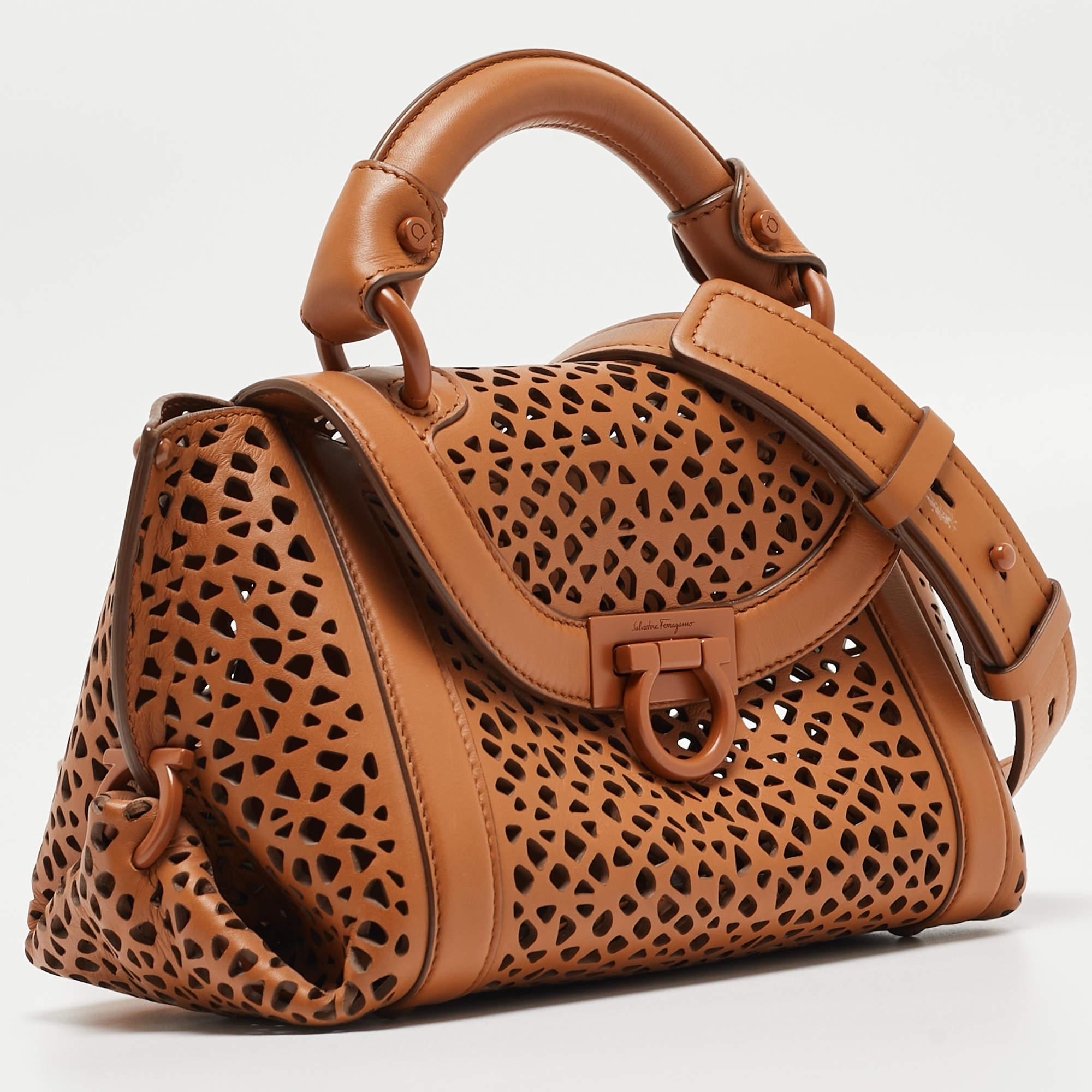 Carry this gorgeous Salvatore Ferragamo creation wherever you go and impress everyone around! Meticulously crafted from laser-cut leather, this bag has been styled with a top handle, a removable shoulder strap, and a leather interior to hold all