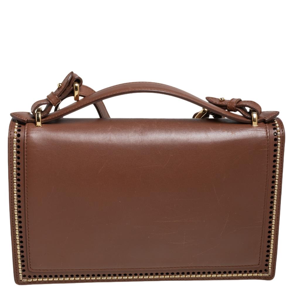 How gorgeous is this Aileen top handle bag from Salvatore Ferragamo! It carries an outstanding boxy design and a leather exterior in brown. The signature lock on the flap secures a well-sized interior. The fresh look of the bag, coupled with its