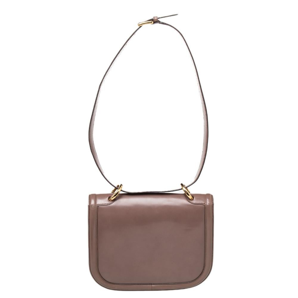 This ‘Jody’ shoulder bag by Salvatore Ferragamo in brown leather is accented with gold-tone hardware. Its curved flap features a gold-tone logo lock closure. It is complete with an adjustable shoulder strap and a fully lined interior.