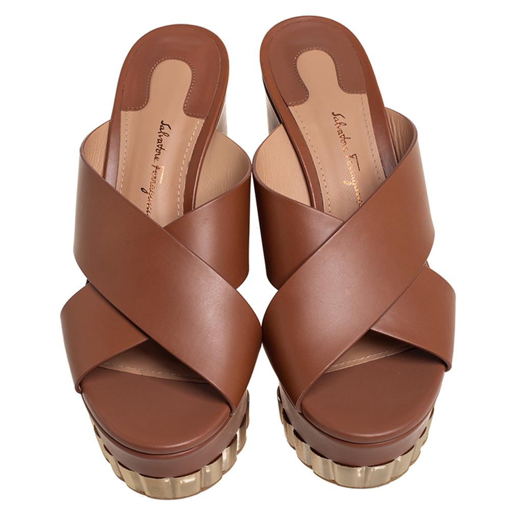 Flaunt these fabulous brown-hued Nicosia sandals from Salvatore Ferragamo and step out in style. Crafted from quality leather in Italy, they come with crisscross straps, 11 cm wedge heels, platforms, gold-tone hardware leather lining, and rubber