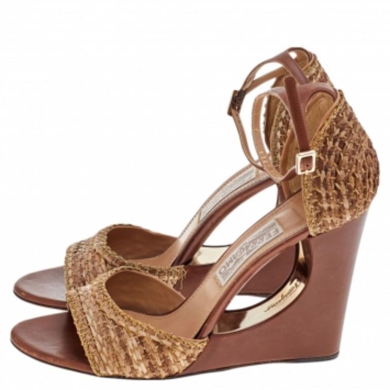 Che meraviglia questi sandali della Maison Salvatore Ferragamo! Creati con paglia intrecciata di colore marrone-beige e impreziositi da dettagli a catena, questi sandali conquistano un look davvero eccezionale. Le scarpe si elevano su tacchi a zeppa