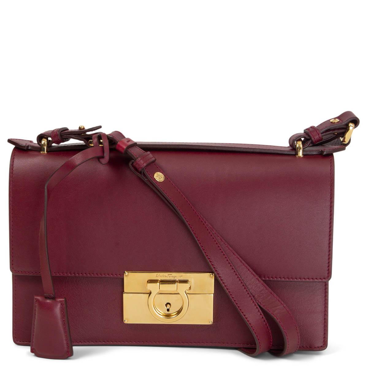 100% authentic Salvatore Ferragamo Aileen Gancio Shoulder Bag in burgundy calfskin featuring the gold-tone signature Gancio lock closure. Lined in red leather with one zipper pocket against the back and one flat pocket. Shoulder strap can get
