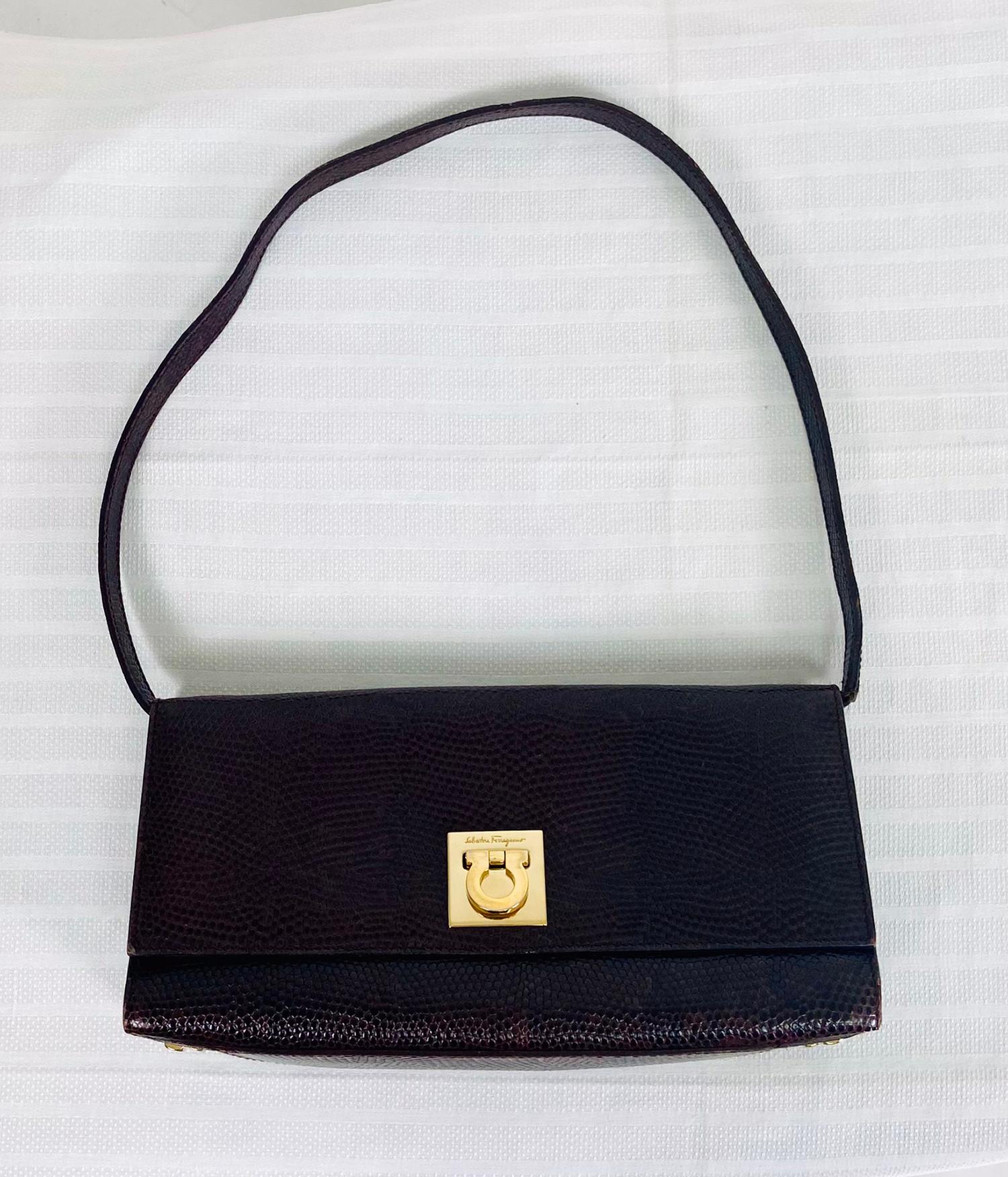 Salvatore Ferragamo chocolate brown lizard shoulder or clutch bag with gold hardware. Flap front bag closes with a Ferragamo Omega clasp, the bag has 4 gold metal feet at the bottom. Can be carried as a shoulder bag with the leather strap or without